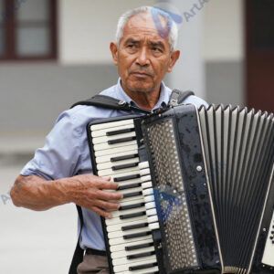 Пожилой мужчина играет на гармошке во дворе.
