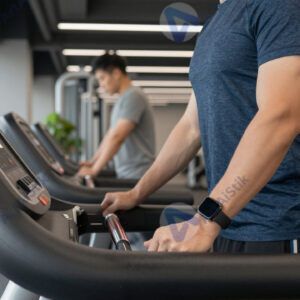 Взрослый мужчина в спортивной одежде на беговой дорожке в зале.