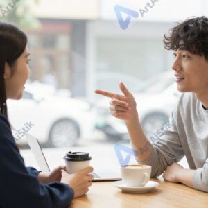 Двое разговаривают в кафе за столиком.