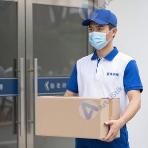 Курьер в фирменной форме несёт коробку к подъезду.