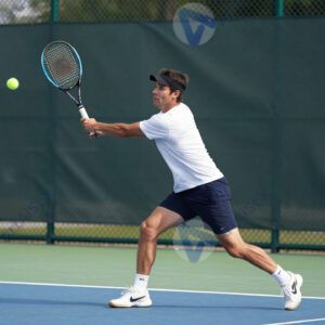 Спортсмен отбивает мяч ракеткой на теннисном корте.