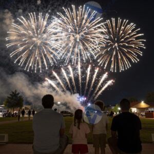 Семья смотрит фейерверк на городской площади ночью.