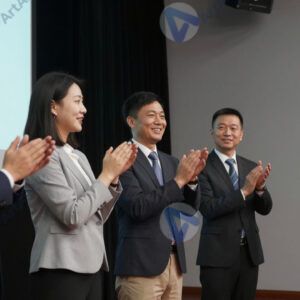 Группа менеджеров аплодирует спикеру на сцене.