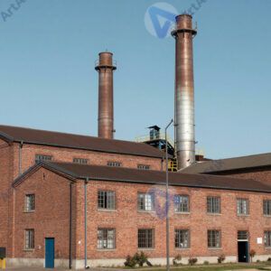 Фабрика с красными кирпичными корпусами и высокими трубами.