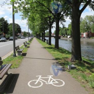 Улица вдоль реки с велодорожкой и лавочками.