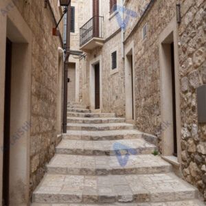 Узкий переулок с каменными стенами и ступенями вниз.