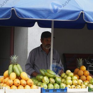 Уличный торговец фруктами под ярким навесом.