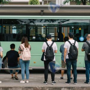 Группа людей ждёт автобус у остановки с навесом.