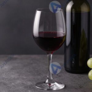 Красное вино в бокале на фоне бутылки и винограда.