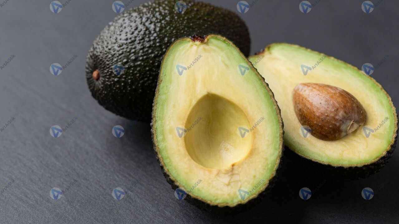 Авокадо разрезанный, косточка и мякоть, тёмный фон. Авокадо разрезанный