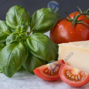 Пучок свежего базилика рядом с помидорами и сыром.