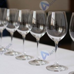 Ряд бокалов для вина на белой скатерти.