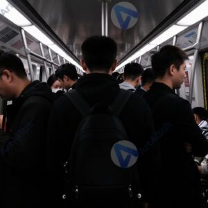 Силуэты людей в переполненном вагоне метро при сильной контровой подсветке.