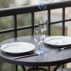 Небольшой столик на балконе с двумя тарелками и стаканами.