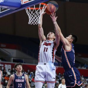 Баскетболисты в прыжке борются за мяч у корзины.