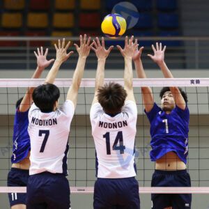 Игроки в волейболе прыгают на совместный блок у сетки.