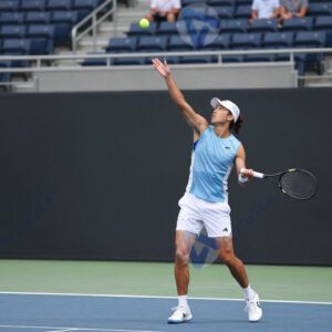 Теннисист подбрасывает мяч перед подачей.