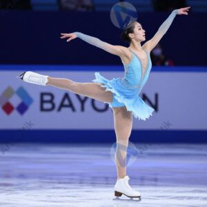 Фигуристка выполняет прыжок на льду в ярком костюме.