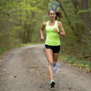 Женщина бежит по лесной тропе в яркой спортивной форме.