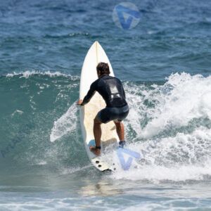 Серфингист гребёт на доске к волне