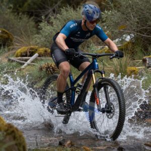 Маунтинбайкер пересекает ручей на скорости