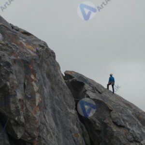 Скала и маленькая фигурка альпиниста вдалеке