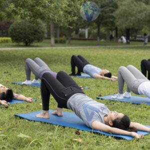 Группа людей на outdoor‑тренировке в парке с ковриками.