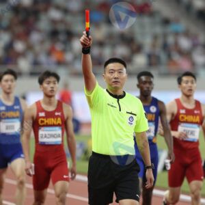 Судья поднимает пистолет для старта