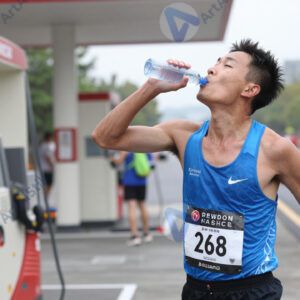 Марафонец пьёт воду на пункте питания во время забега.