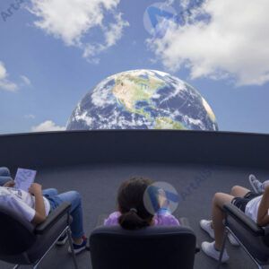 Дети в планетарии лежат в креслах и смотрят на купол с небом.