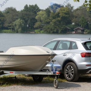 Автомобиль с прицепом‑лодкой на парковке у озера.