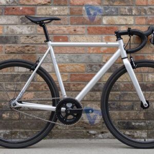 Велосипед‑фиксив с минималистичной рамой у кирпичной стены.