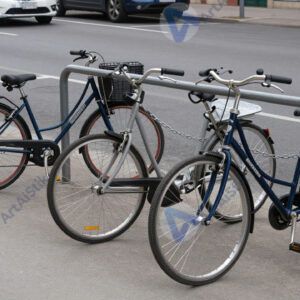 Городской парковочный столб с прикованными цепями велосипедами.