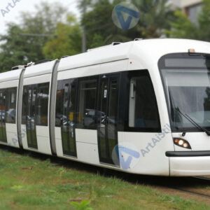 Современный трамвай с низким полом уходит вдоль зелёной полосы.