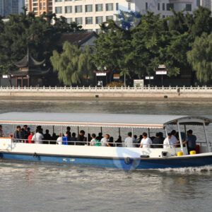 Лодка‑водное такси перевозит людей по городской реке.