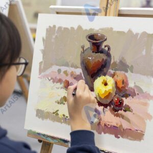 Ученик в художественной школе рисует натюрморт с вазой и фруктами.