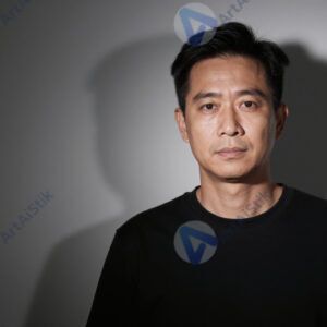 Студийный портрет с одним источником света и жёсткой тенью на фоне.