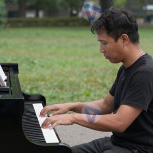 Уличный пианист играет на пианино в парке.