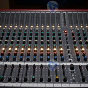 Студийный микшерный пульт с множеством бегунков и лампочек.