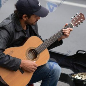 Музыкант на улице с гитарным футляром для монет.