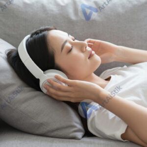 Девушка в наушниках лежит на диване