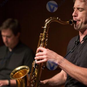 Музыкант на саксофоне в джаз‑клубе под тёплым светом.