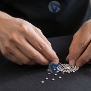 Человек клеит стразы на ткань