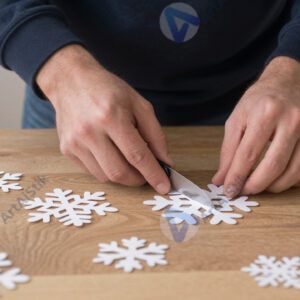 Человек вырезает снежинки из бумаги перед праздником.