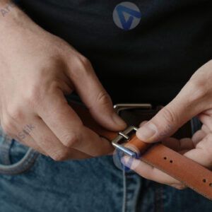 Мастер примеряет кожаный ремешок к металлической пряжке.