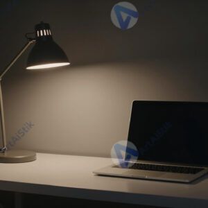 Стол с одной лампой и ноутбуком в тёмном офисе вечером.