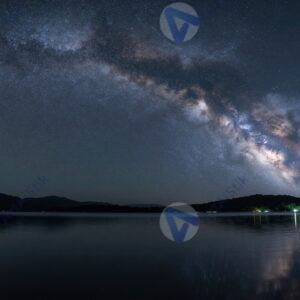 Ночное звездное небо над спокойным озером и силуэтами деревьев на горизонте